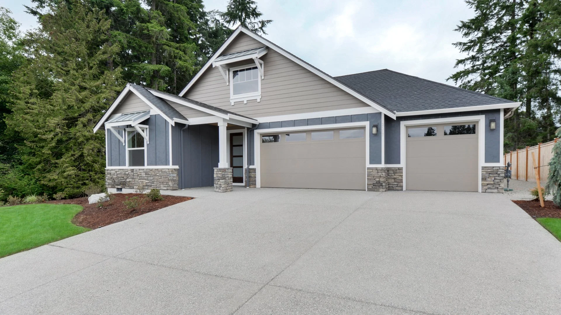 Modern single-family home exterior featuring a driveway, garage, and landscaped front yard.